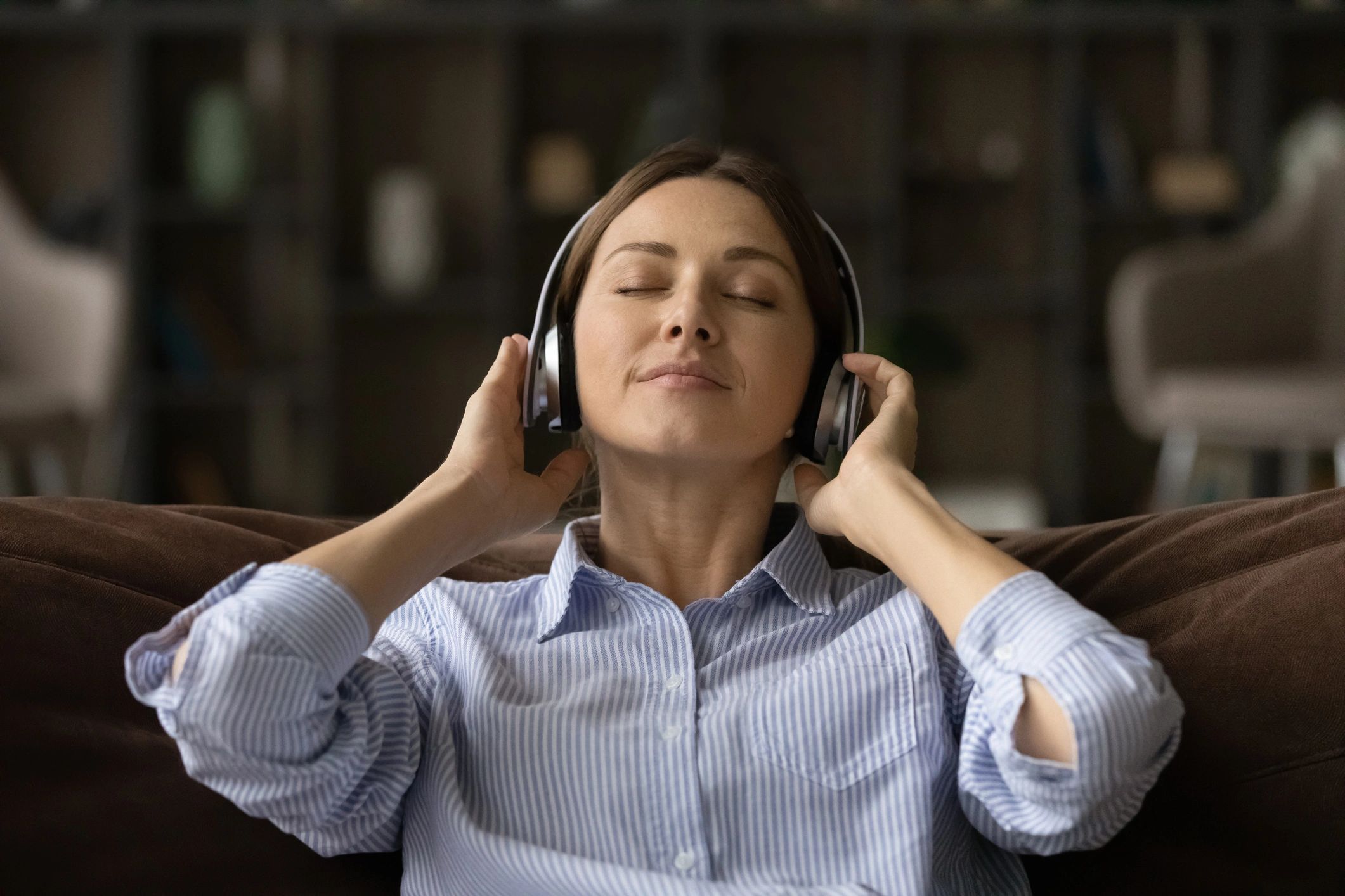 Woman relaxing on a couch listening to audio with headphones