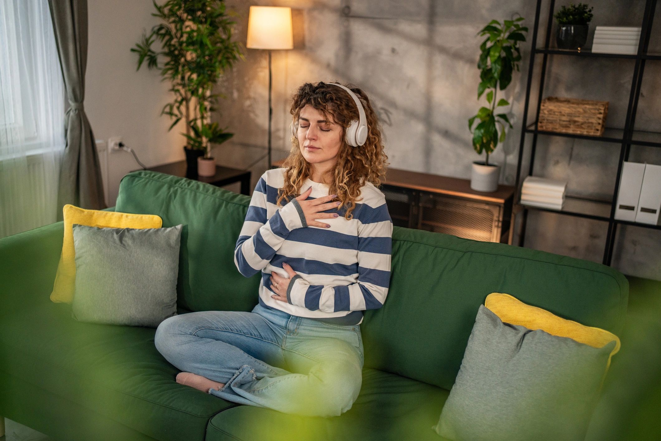 A young woman practices guided meditation in the living room