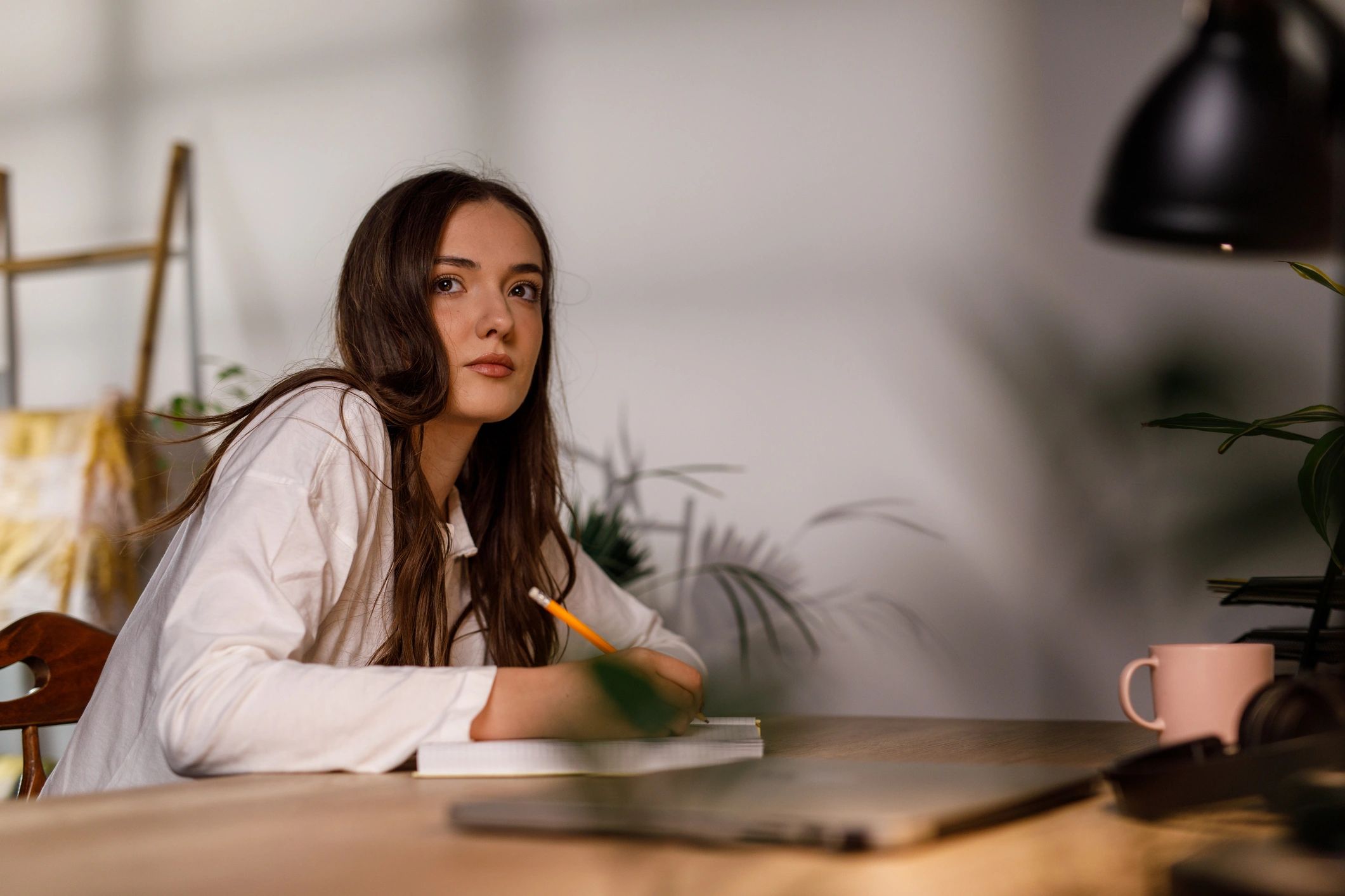 Young woman in pajamas writing in a diary in the morning