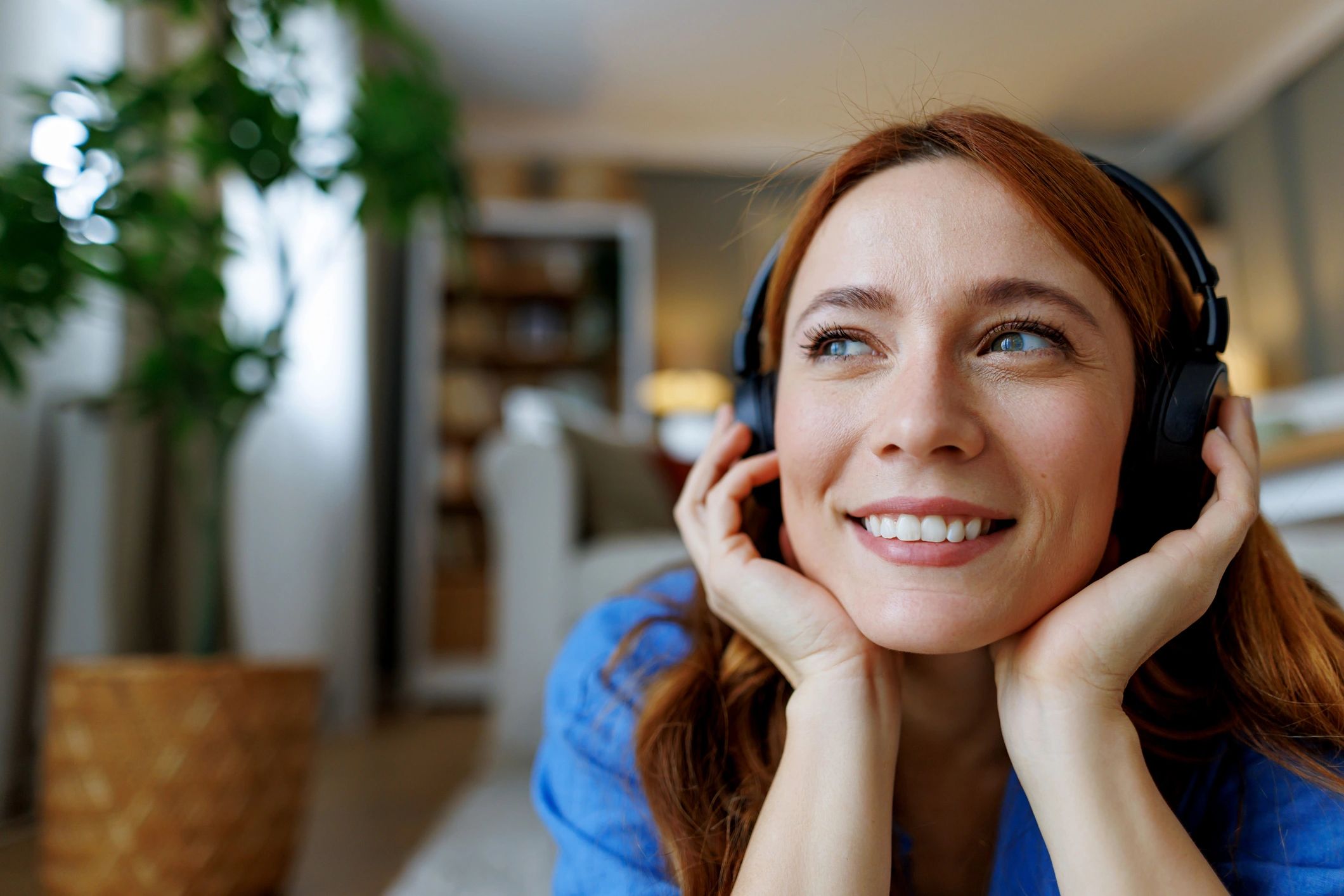 Young Woman Listening to Music with Headphones and Smiling at Home