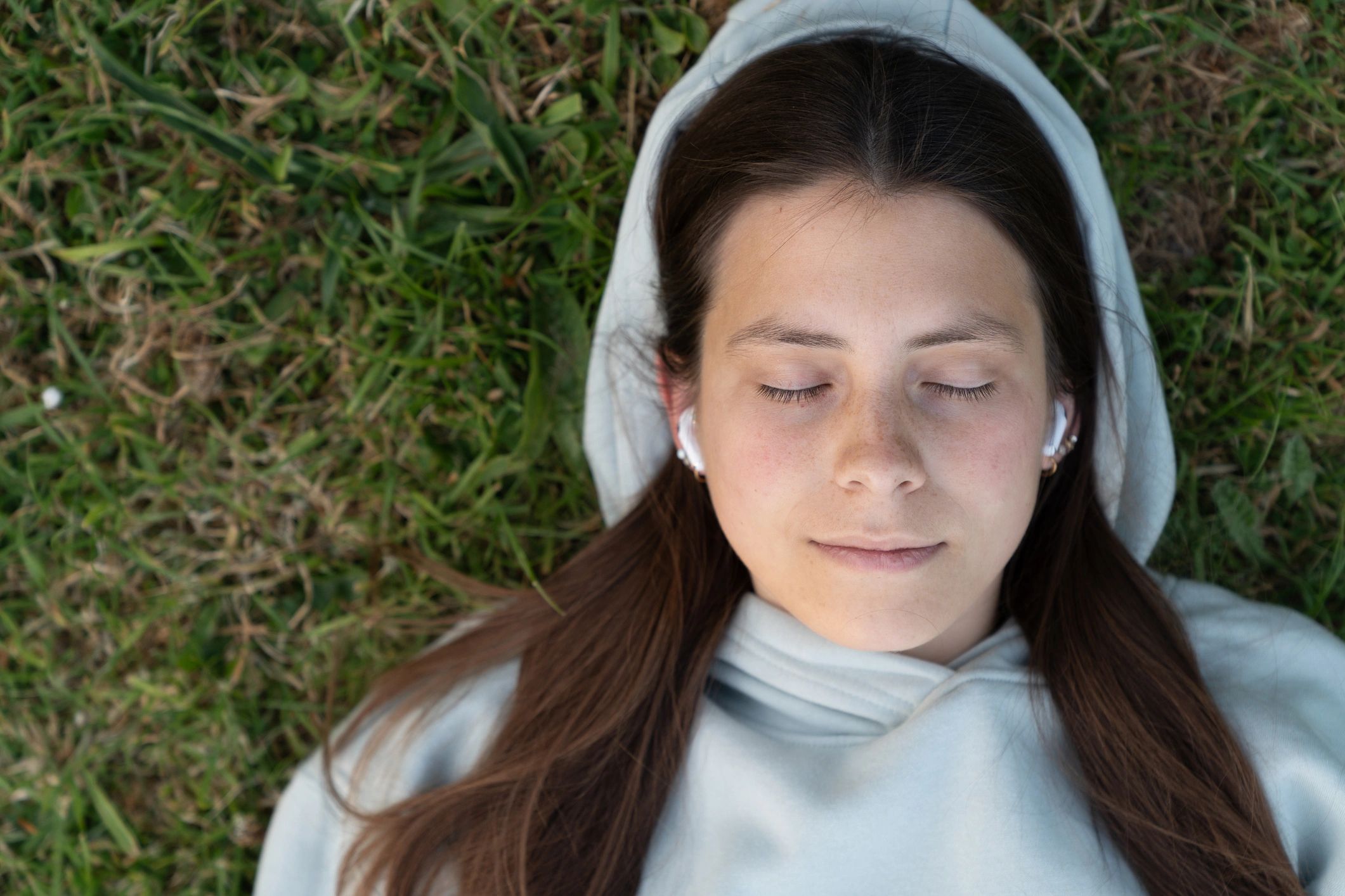 Young woman relaxing outdoors listening to audio with earbuds